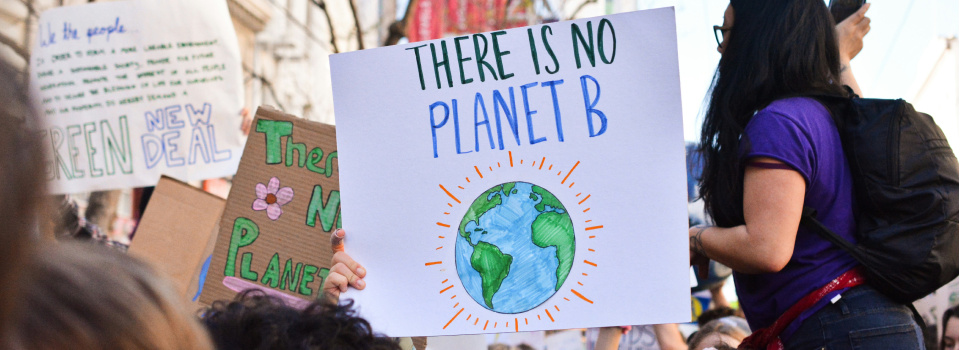A group of protestors holding placards. One has a picture of the earth and says "There is no Planet B"